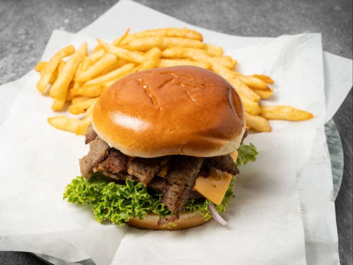 Gyro cheeseburger with American cheese, vegetables, sauces, and fries at Mayo Grill