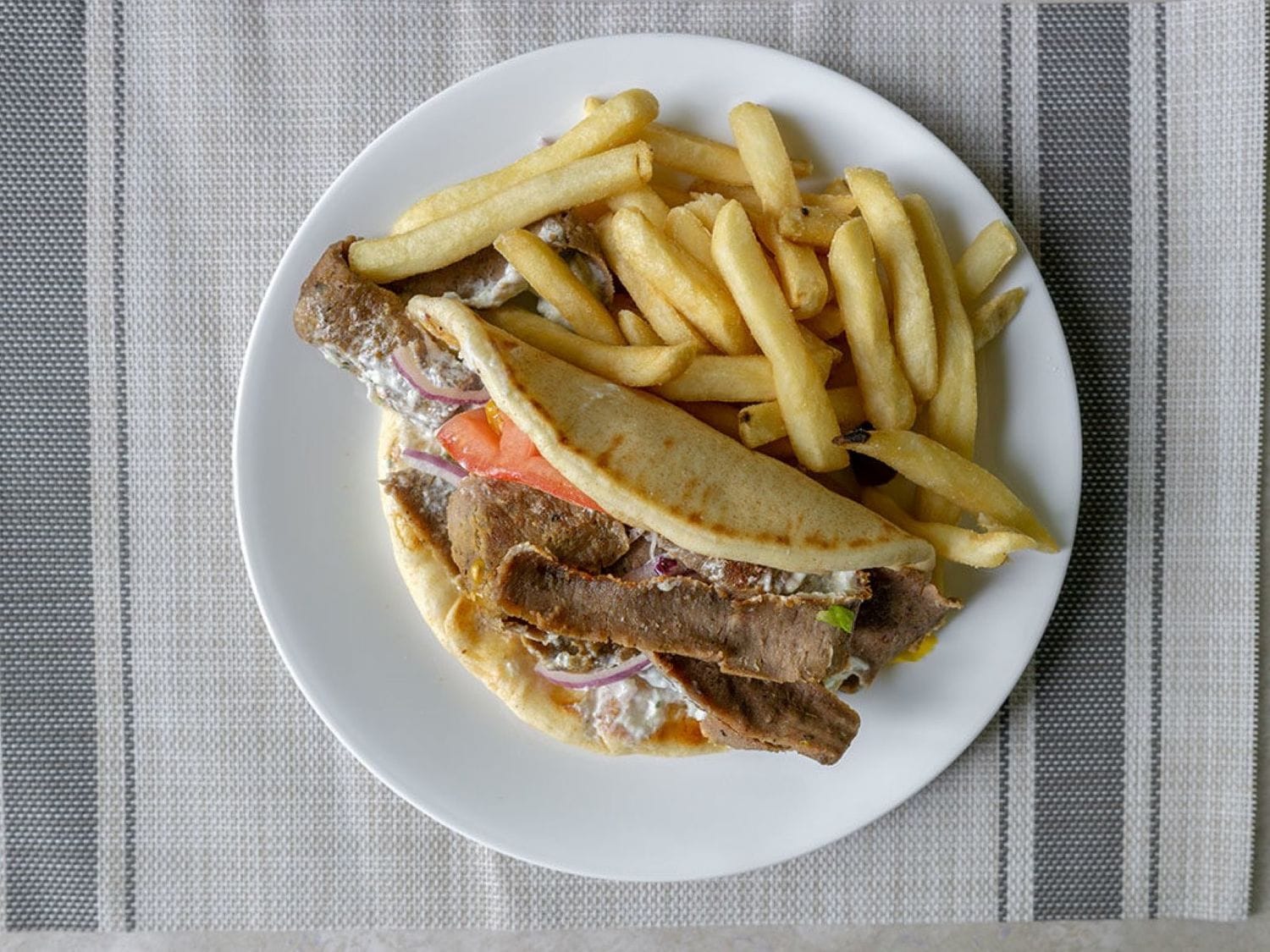Gyro sandwich with pita, tomato, onion, tzatziki, and fries at Mayo Grill in Aurora