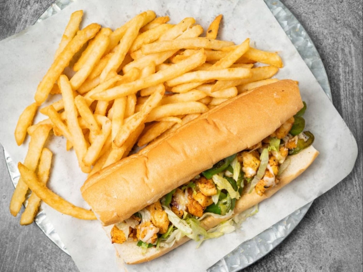 Philly Chicken sandwich with peppers, onions, cheese, vegetables, and fries at Mayo Grill